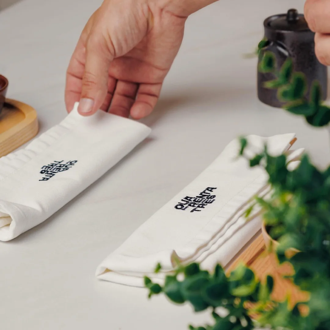Nhdesign project Quarenta e três: Hand placing napkin with Quarenta e Três visual identity on dining table
