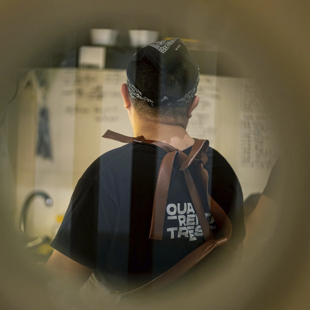 Nhdesign project Quarenta e três: Team member wearing Quarenta e Três uniform working in kitchen, seen from behind