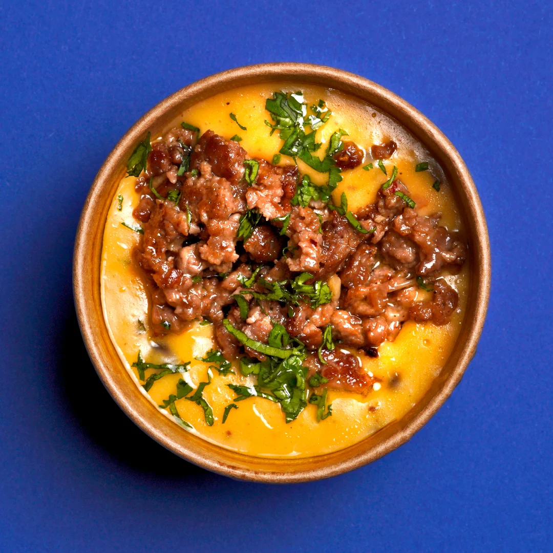 Nhdesign project SMASH VS THREAT: Bowl with minced meat and garnish on blue background