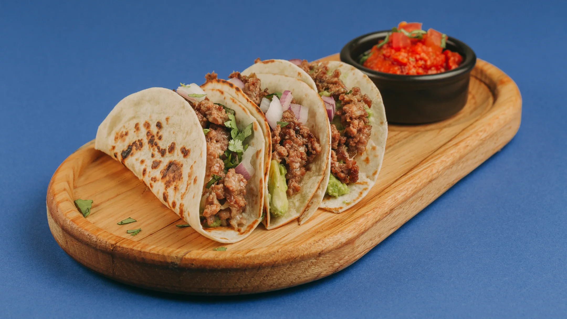 Nhdesign project SMASH VS THREAT: Set of tacos on wooden plate served with red spicy sauce