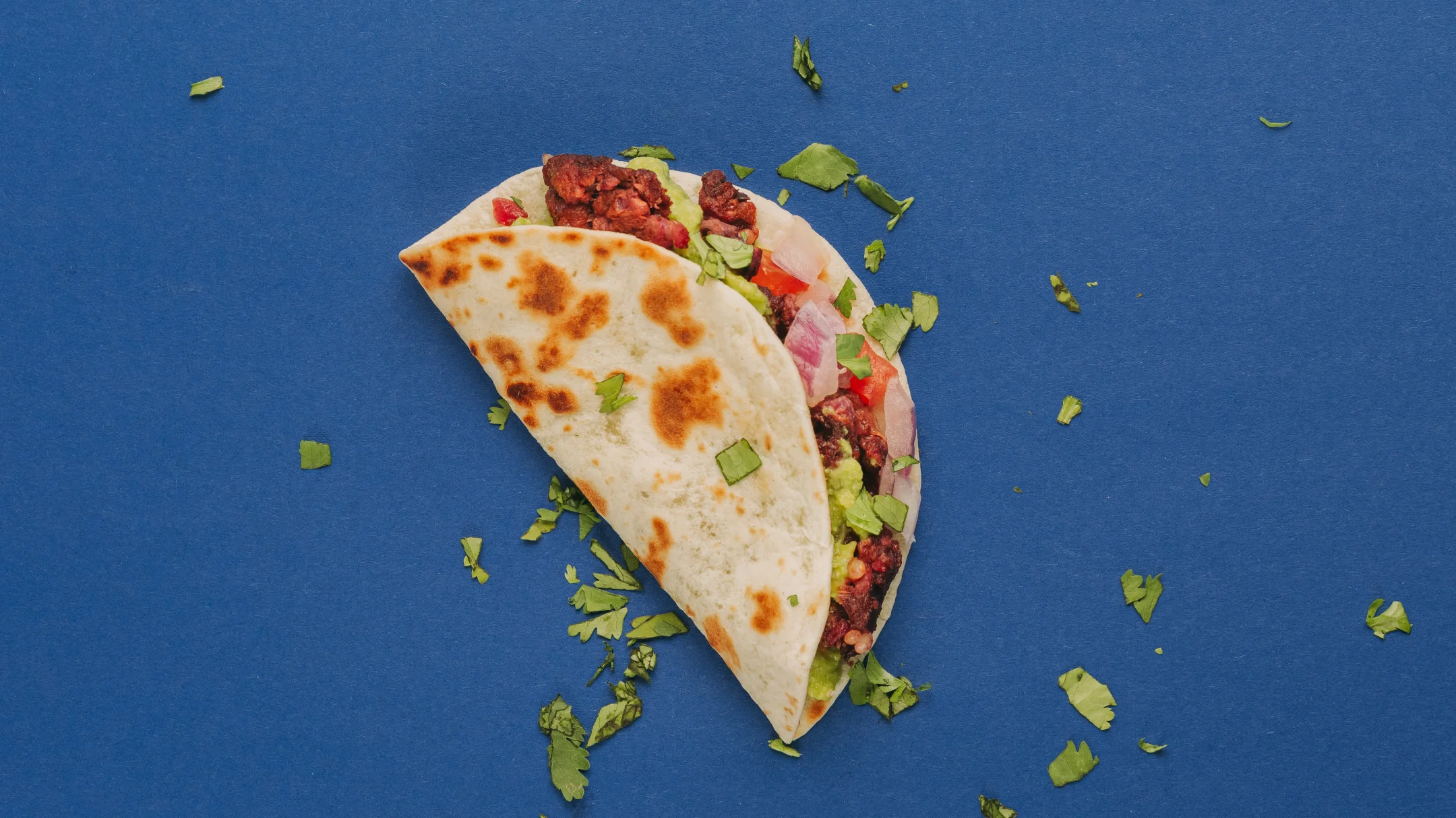 Nhdesign project SMASH VS THREAT: Individual taco served on blue background with green garnish