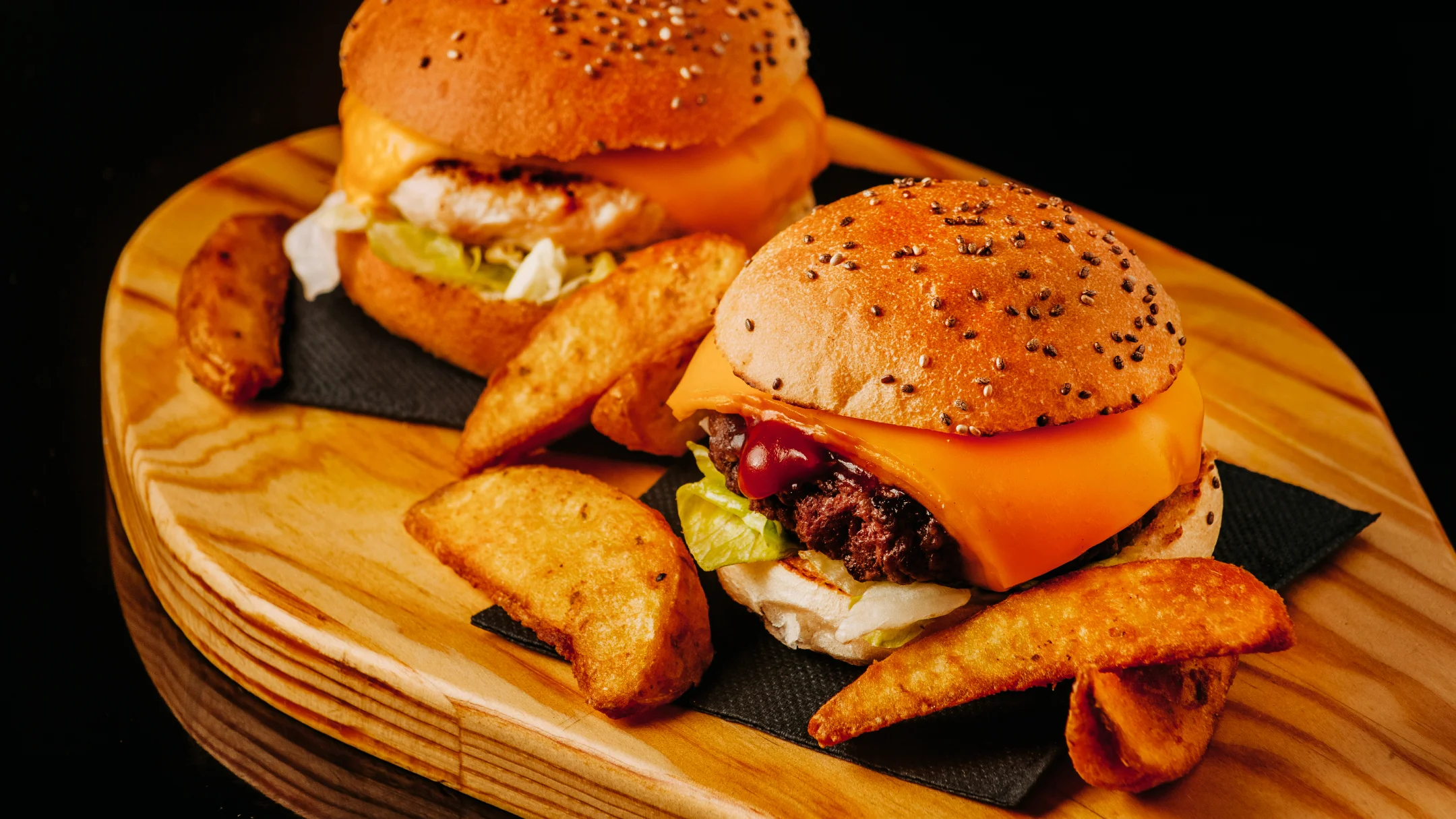 Nhdesign project DANS: Three DANS burgers served on wooden board with fries