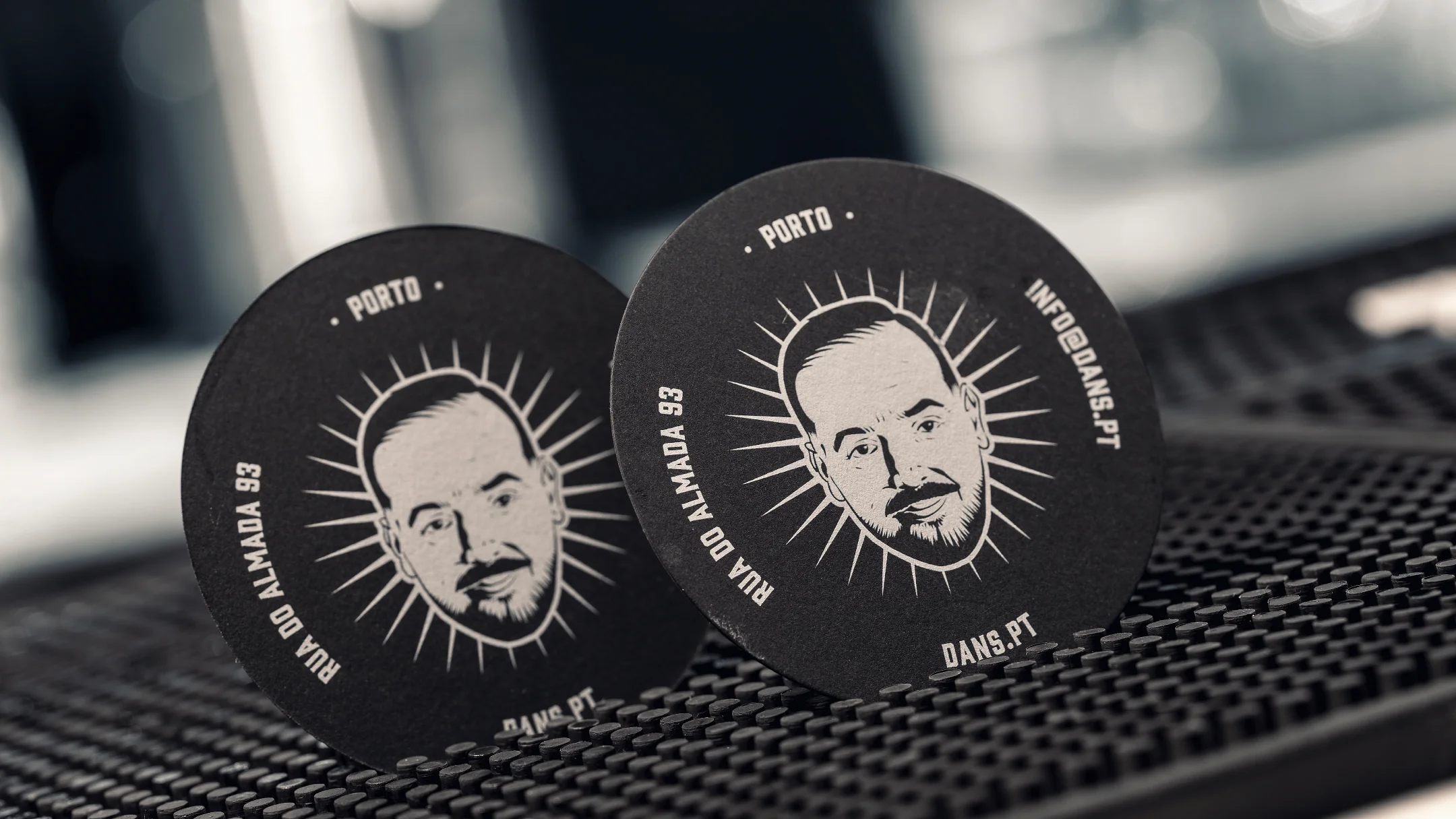 Nhdesign project DANS: Black DANS coasters with white logo on bar counter