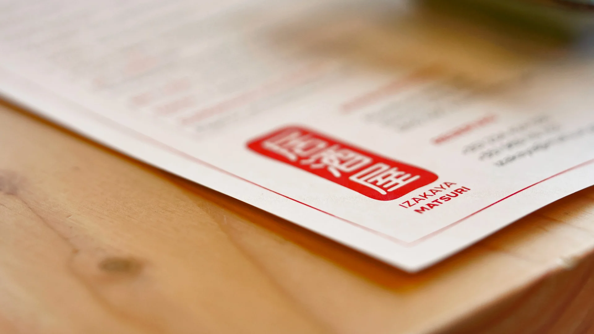 Nhdesign project Izakaya Matsuri: Red and white logo on placemat in close-up shot.