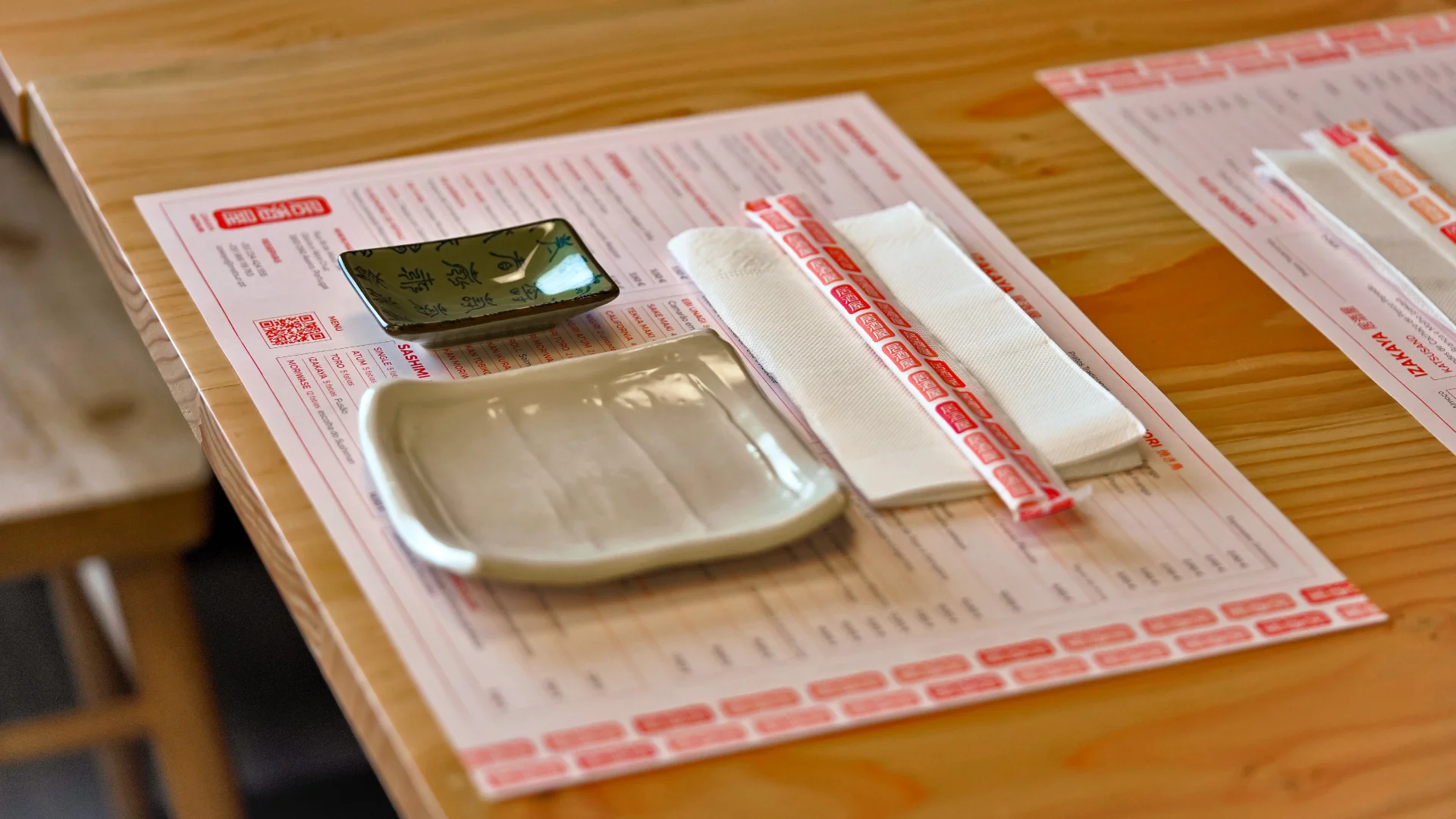 Nhdesign project Izakaya Matsuri: Neatly arranged plate, bowl, and chopsticks on a table with branded chopsticks and placemat.