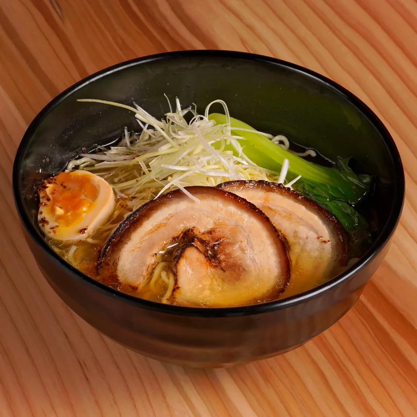Nhdesign project Izakaya Matsuri: A bowl of ramen topped with meat and mixed vegetables on wooden table.