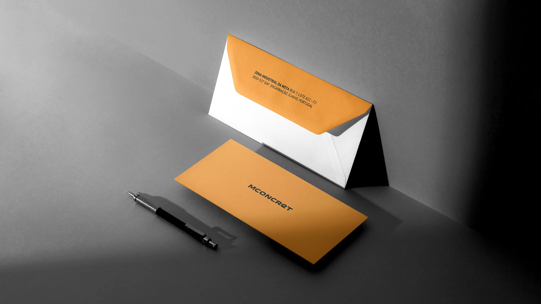 Nhdesign project Mconcret: Mconcret corporate envelopes in orange and white, with pen.